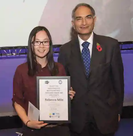 Rebecca Mile receiving her award from Raj Thakker