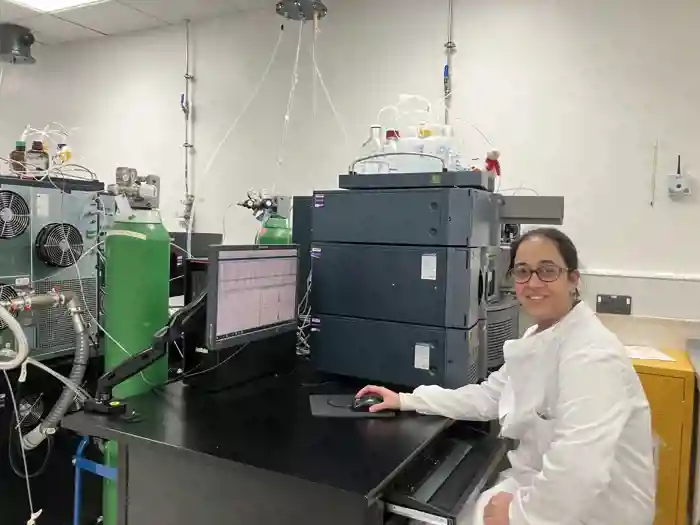 Photograph of Fozia Shaheen seated in the laboratory, smiling at the camera